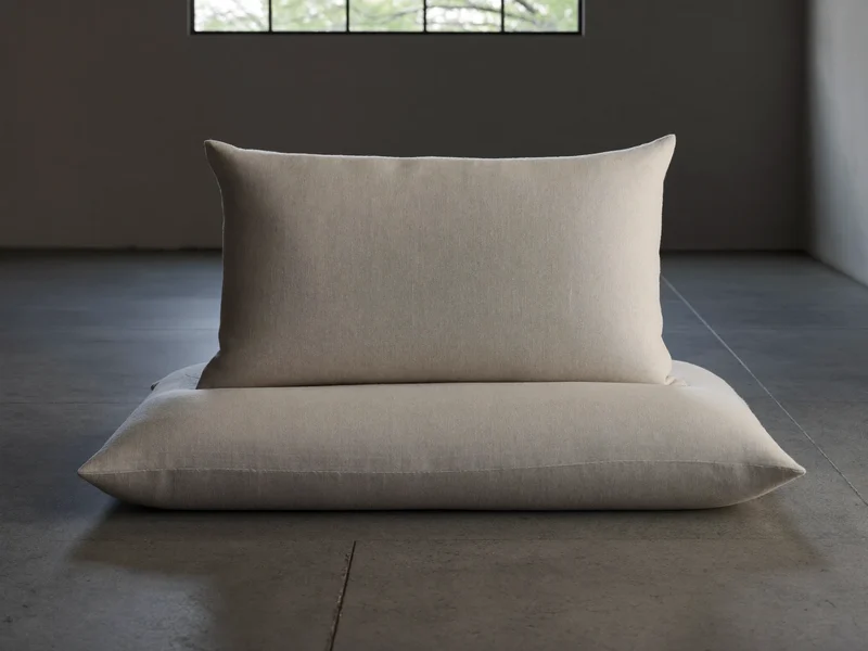 Coussin de méditation en lin écru posé près d'une fenêtre basse